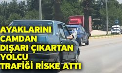 Ayaklarını camdan dışarı çıkartan yolcu trafiği riske attı